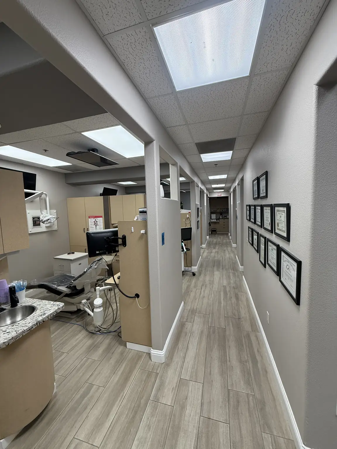 Office hallway with framed certificates looking into a treatment room