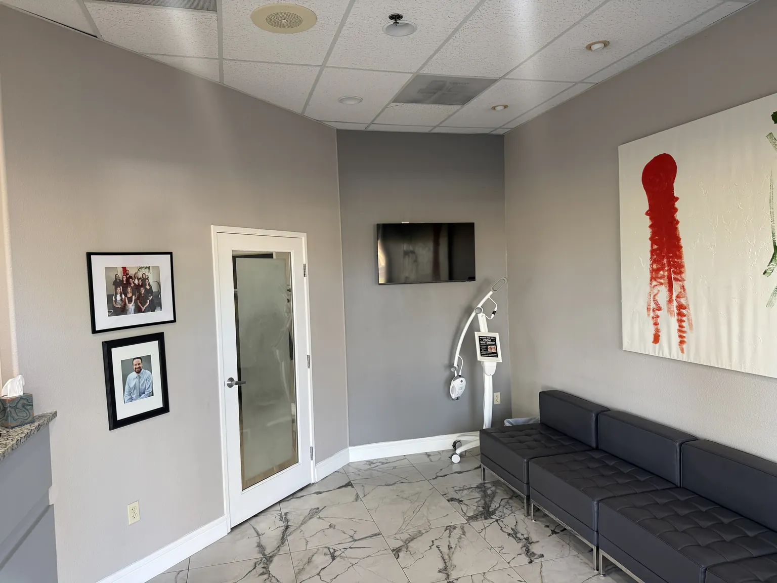 Waiting area with a tufted sofa, artwork, and marble-look tile at the Elverta Road office